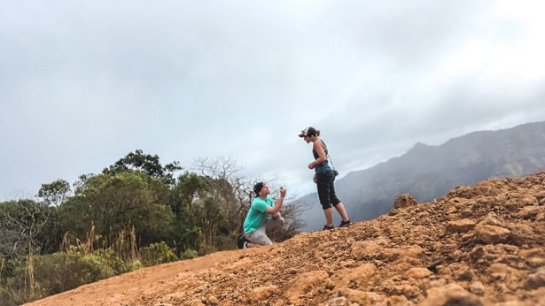 John down on one knee proposing marriage to Brittany on a Hike to Waipo'o Falls in Kauai Hawaii