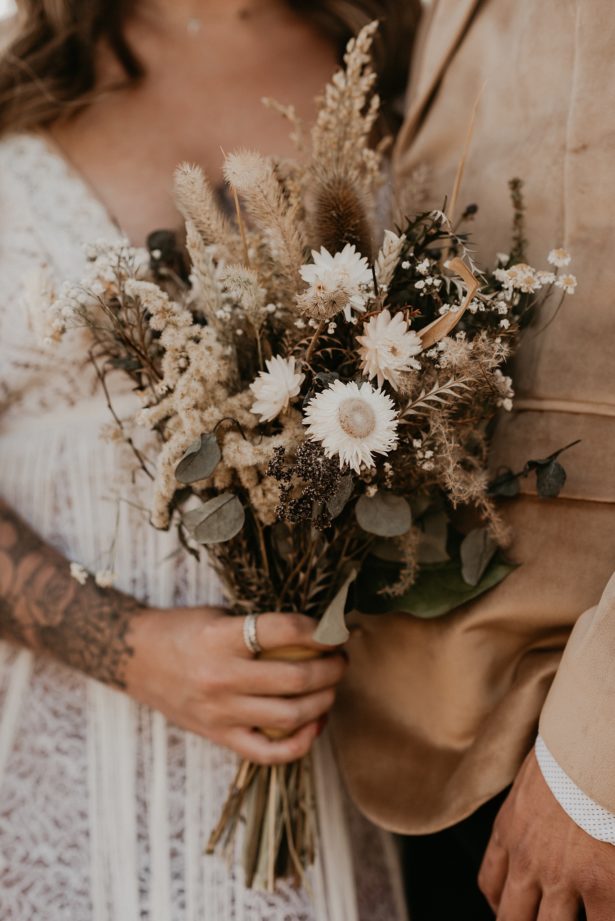 Close up of bride holding her bouquet of dried flowers next to her husband